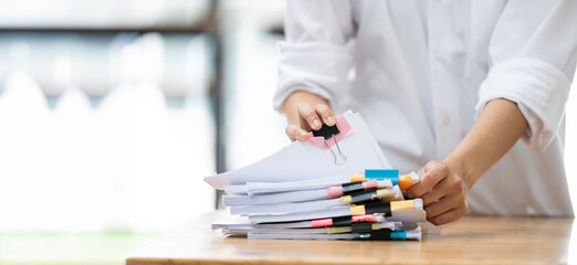 Businesswoman hands working in Stacks of paper files for searching and checking unfinished document...