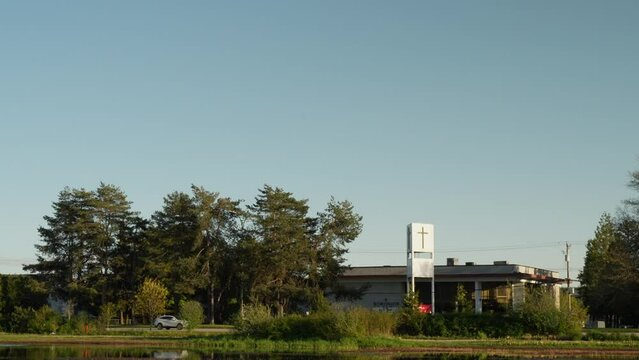 Church building with cross surrounded by trees and pond in a serene park