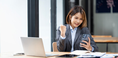 Beautiful asian woman using smartphone, exciting and celebrating with good news of business...