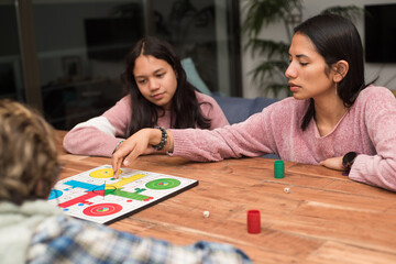 Fototapeta premium Mother moving chip on ludo board game playing in family at home