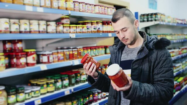Adult man buyer in casual clothes chooses lecho in store
