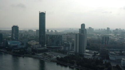 Top view of modern gray city in cloudy weather. Stock footage. Grey cloudy city with river and fog. Cloudy day hanging over modern city