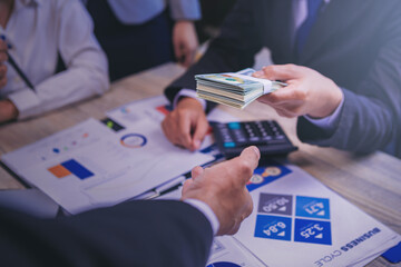 Businessman paid Dollars money banknotes for business investment and shaking hands with partnership.