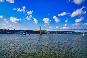 Splendid panorama of the Pont de l'lle bridge with the Montmorency falls in the background taken from cruise boat on a bright summer day on the St.Lawrence river near Quebec city, Canada
