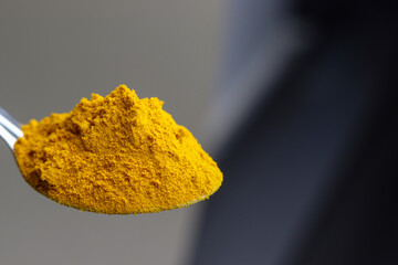 Turmeric powder in Steel spoon with plain background.