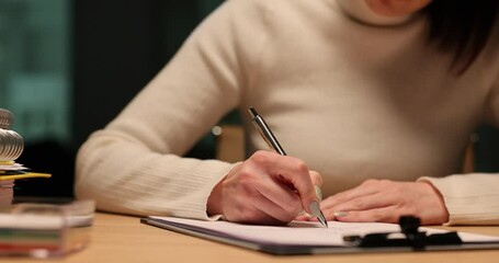 Woman writes at desk late at night in office