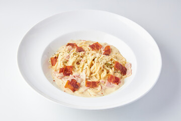 Spaghetti Carbonara topped with ham and bacon served in white plate isolated on white background. italian food.