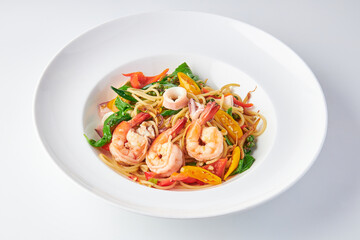 Spicy spaghetti with mixed seafood (shrimp and squid) and herb (Red pepper, yellow pepper, galangal, basil leaves, Turkey berry) isolated on white background.