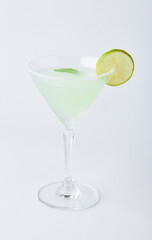 Glass of Classic Margarita cocktail decorated with sliced lemon, mint leaves and salt is on the rim of the glass isolated on white background.