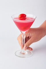 Hand holding Pink daisy cocktail in transparent glass isolated on white background.