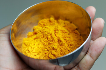 Close up of Turmeric powder in stainless steel bowl.