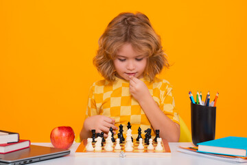 Portrait of cute child play chess on studio isolated background. Thinking child. Chess game for kids. Intelligent, smart and clever school boy.
