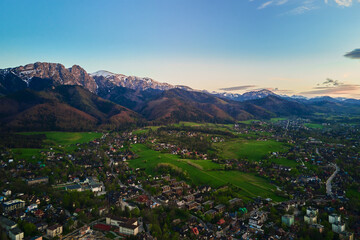 Aerial view of Tatra mountains and Zakopane town at sunset. Panoramic landscape with mountain ranges and green valleys near village. View on Giewont, Poland