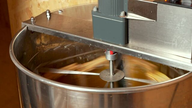 Рrocess of extracting honey from honeycombs in a honey extractor. Close-up. Beekeeping. Honey production.