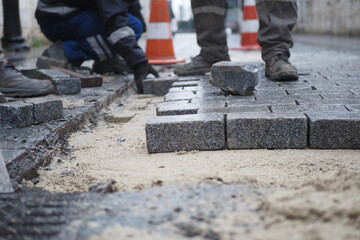 a worker laying concrete bricks on each other for building a new sidewalk