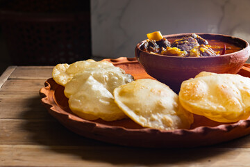 luchi or puri and mutton curry or laal maas served on earthen plate. Luchi is indian flatbread made of flour and deep fried. traditional indian meal.