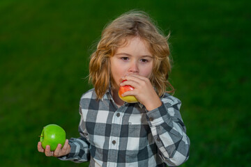 Fresh ripe apple for children. Kid enjoy picking apple. Child bitten apple outdoor on summer green grass background.