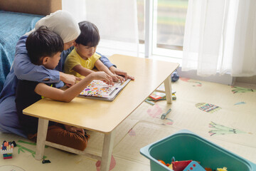 mother with his two son reading a books in a messy living room, concept of parenting and learning