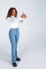 Chica negra afro usando teléfono móvil. Mujer haciendo selfies. Fotografia con móvil....