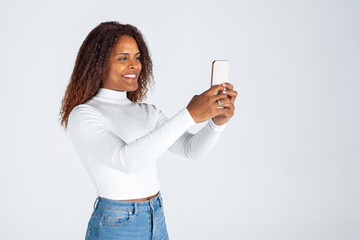 Chica negra afro usando teléfono móvil. Mujer haciendo selfies. Fotografia con móvil....