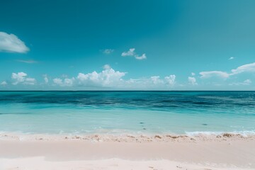 Obraz premium A pristine beach with clear blue water and white sand under a bright blue sky with fluffy clouds.