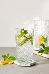 A refreshing summer drink or alcoholic cocktail with ice, mint and lemon on a sunny day. A fresh healthy cold lemonade drink. Sparkling water with lemon