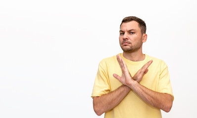 Male person wearing yellow t-shirt stands on white background and gesturing a refusing,...