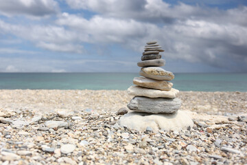Sandstone are stacked into a pyramid shape on sea and cloud background and copy space.