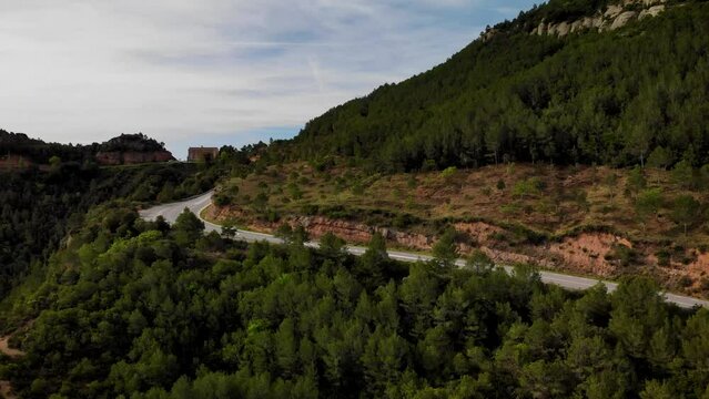 Mountain road with traffic pssing by at Montserrat mountain, Barcelona, Cataloia, Spain. High quality 4k drone view footage