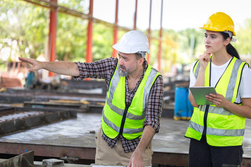 Senior engineer and female foreman team checking project at precast concrete factory site, Caucasian engineer and worker in hardhats discussing on construction site
