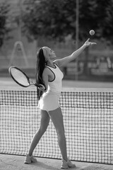 Sexy sporty woman on tennis court. Beautiful female tennis player with tennis racket and balls in the sport club. Sports Fashion. Girl playing tennis at a clay court holding the racket.
