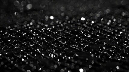  A black-and-white image of raindrops on a repeated black-and-white backdrop  Multiple layers of raindrops on a black background, each captured