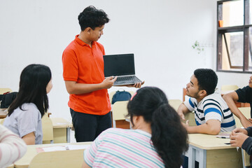 Asian Teacher Holding a Laptop Computer and Talking to Students