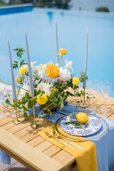 Lemon lies on a plate near a bouquet of flowers on a festive table by the pool