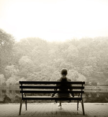 Lonely girl on a bench by the lake