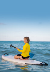 Summer vacation with kids in sea. Kid and Summer sea. Child boy paddling on paddle board or sup. Summer lifestyle. Summer Water sport. Kid Boy swimming with paddle board.