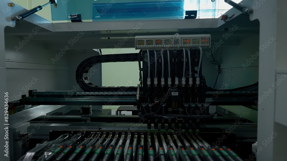 Poster automatic pick and place machine is installing components on circuit board. creative. assembly line 