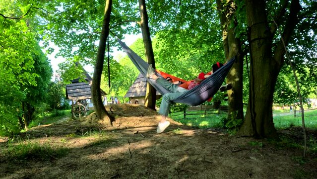 young family of mother father and little son resting on hammocks in public par