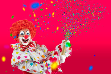 Funny clown pulling carnival cracker. Entertainer Joker in colorful suit and wig.Trickster, jester, pantomime, mime whiteface makeup. Professional actor at event, kids party, circus.