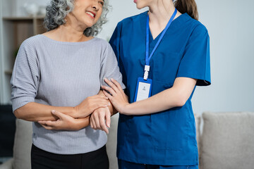 young caregiver assists her elderly woman patient at a nursing home. senior woman is assisted by a...