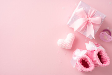 Baby shower themed image with pink booties, crocheted heart, pacifier and gift box on a soft pink...