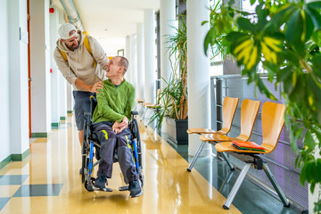 Disabled man and friend walking along in the university corridor