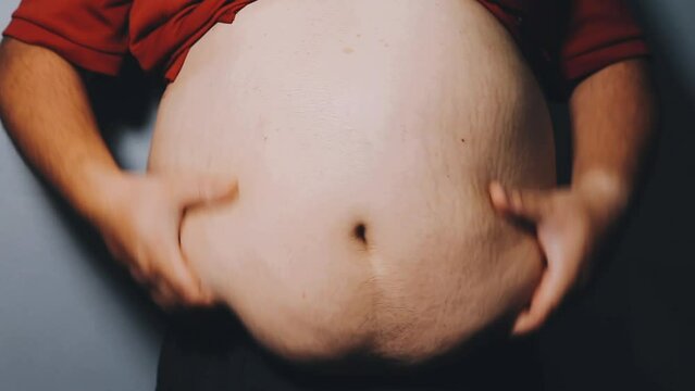 Man pointing own unhealthy big belly with visceral or subcutaneous fats. Pose health risk.