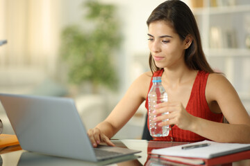 Student drinking water from bottle at home