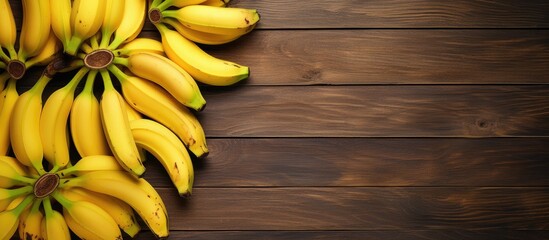 Yellow ripe bananas are laid out in the form of a tree with branches on a wooden textured surface top view. copy space available - Powered by Adobe