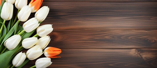 The wooden background showcases a vibrant display of white and orange tulips leaving ample copy space in the image
