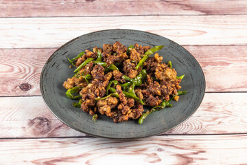 Stir Fried Green Chilli Chicken Dry served in plate isolated on wooden table side view of bangladeshi food