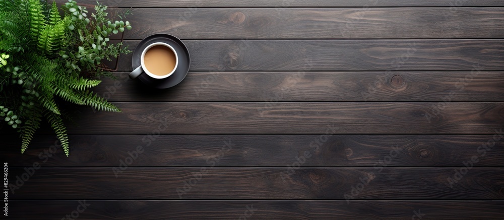 Poster the top down view of a black wooden office desk features a computer keyboard notepad plant and cup o