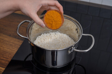 Dodawać przyprawę curry do ryżu w garnku