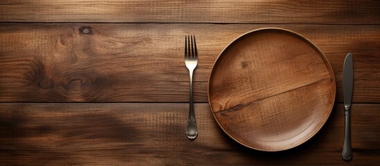 An image of a plate with no food and utensils a spoon and fork placed on a wooden table. Copyspace image
